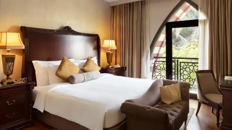 a bedroom with a bed and a chair and a window at Jumeirah Zabeel Saray Dubai in Dubai