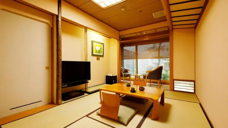 a living room with a table and a television at Kanazawa Hakuchoro Hotel Sanraku -Natural Hot Spring- in Kanazawa
