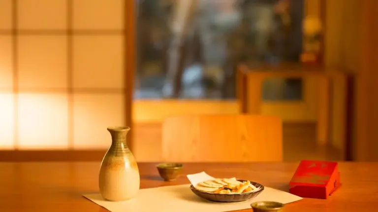 a table with a vase and a bowl of food at Kanazawa Hakuchoro Hotel Sanraku -Natural Hot Spring- in Kanazawa