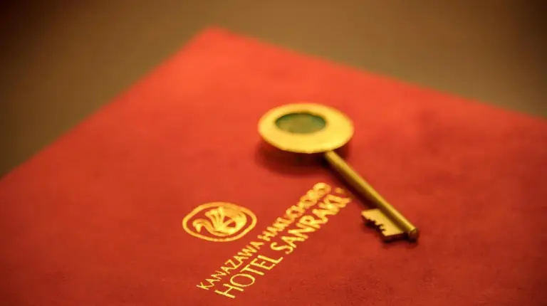 a gold key on top of a red passport at Kanazawa Hakuchoro Hotel Sanraku -Natural Hot Spring- in Kanazawa