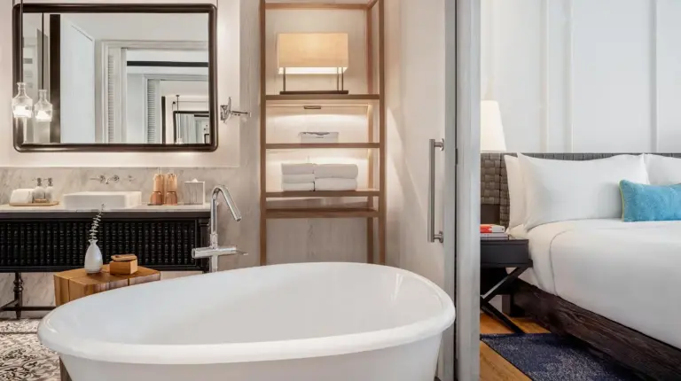 a bathroom with a tub and a bed and a sink at Kimpton Kitalay Samui by IHG in Choeng Mon Beach