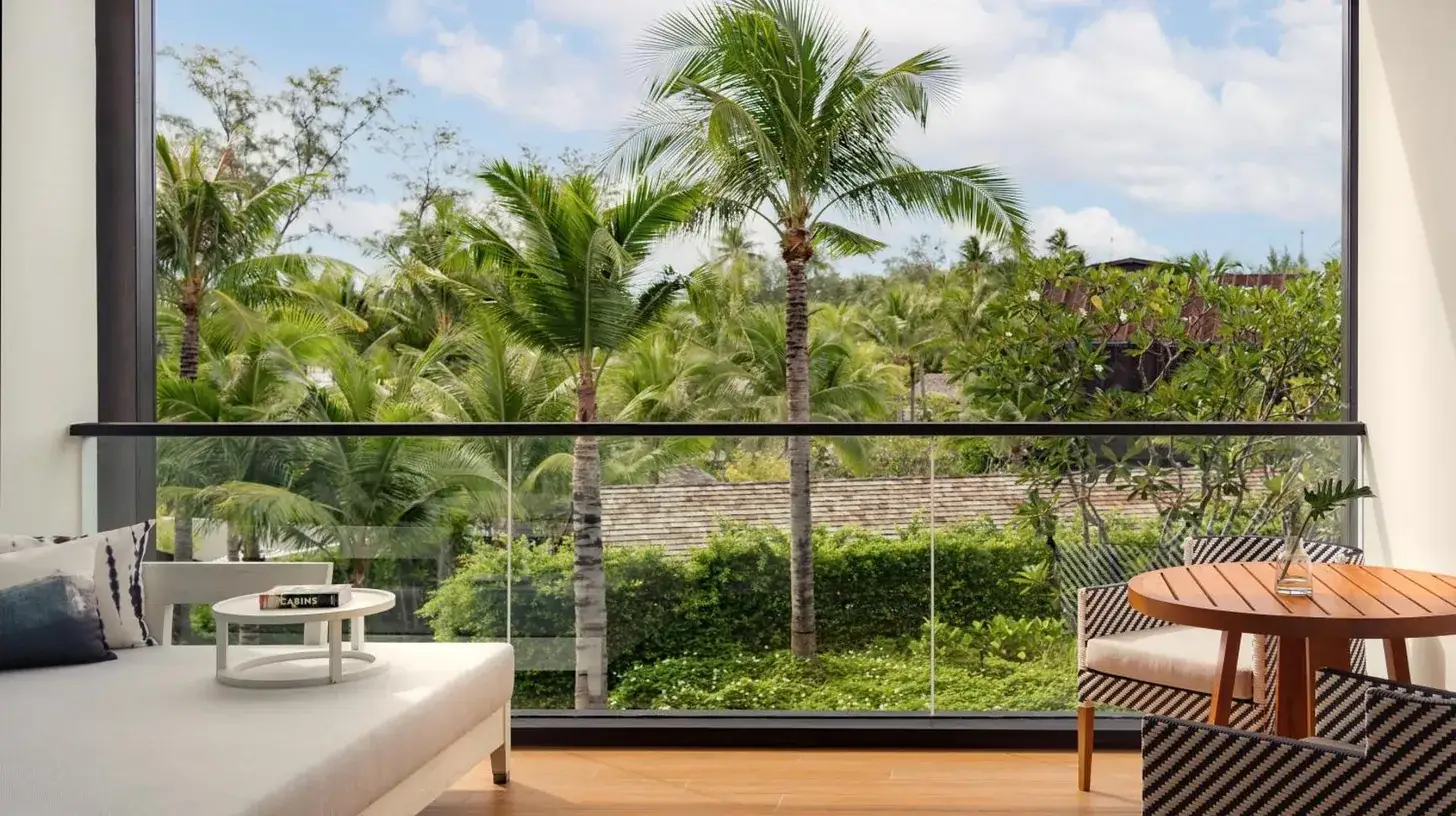 a living room with a large window with palm trees at Kimpton Kitalay Samui by IHG in Choeng Mon Beach