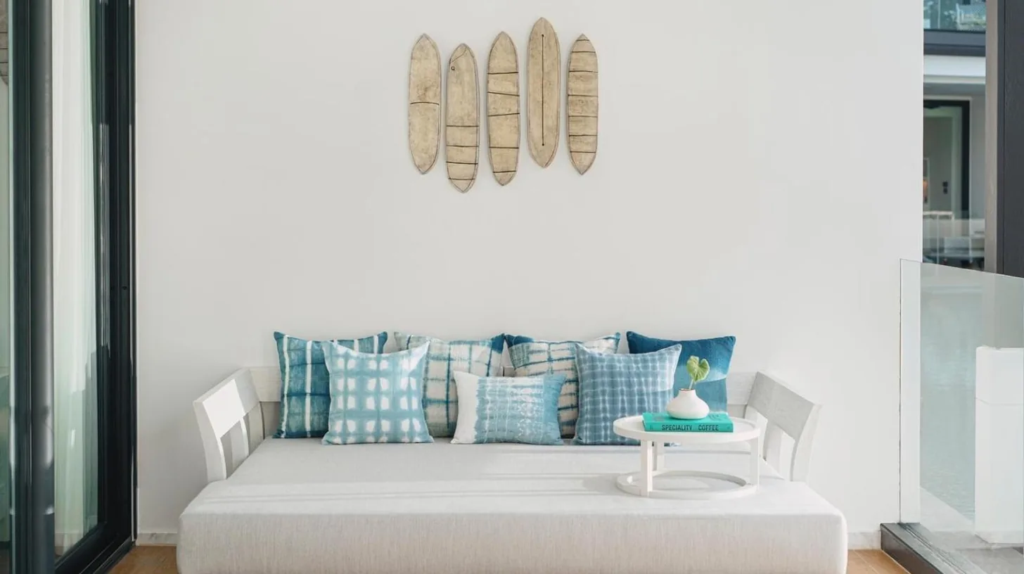 a living room with a couch with pillows and a table at Kimpton Kitalay Samui by IHG in Choeng Mon Beach