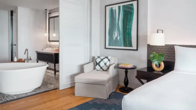 a bedroom with a bed and a tub and a chair at Kimpton Kitalay Samui by IHG in Choeng Mon Beach