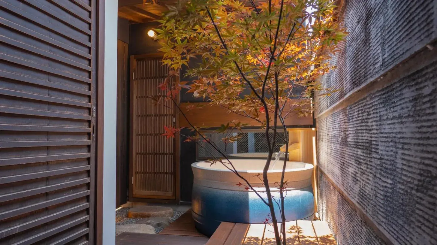a bath tub sitting on a porch with a tree at Kiraku Kyoto Gion in Kyoto