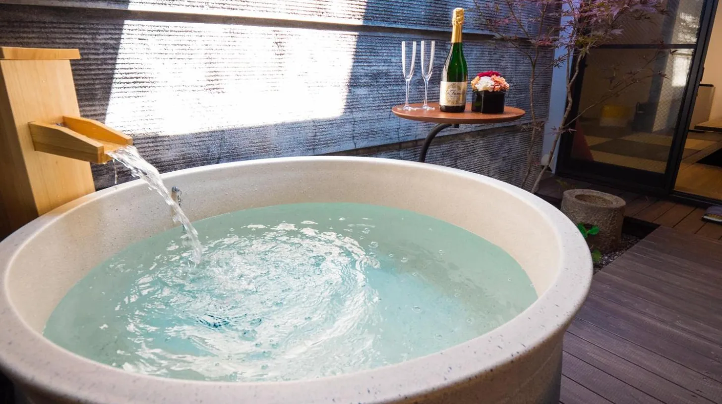 a bath tub filled with water with a bottle of wine at Kiraku Kyoto Gion in Kyoto
