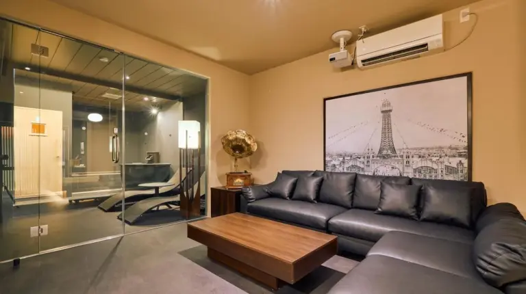 ein Wohnzimmer mit Ledersofa und Tisch bei KONJAKUSO OSAKA TSUTENKAKU MUSHIBUROYA Sauna Villa in Osaka