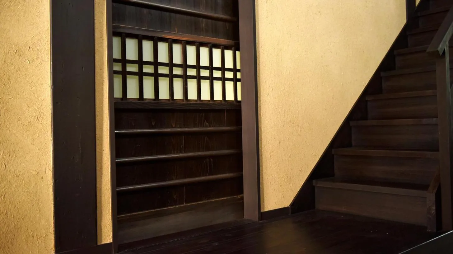 eine Treppe in einem Gebäude mit Holzregalen bei Kuraya Nanseicho in Kyoto