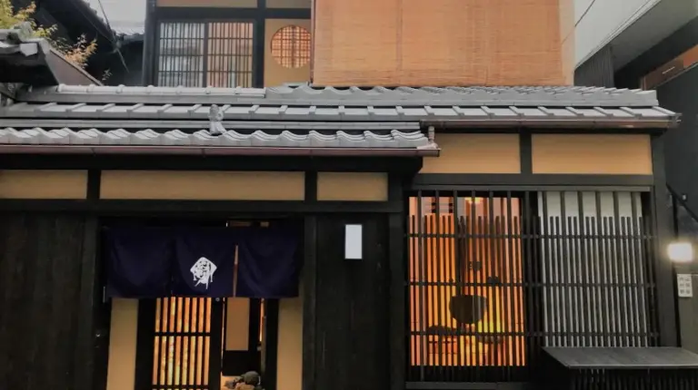 a building with a gate with a flag on it at Kyo no Ondokoro Gokomachi Ebisugawa #3 in Kyoto