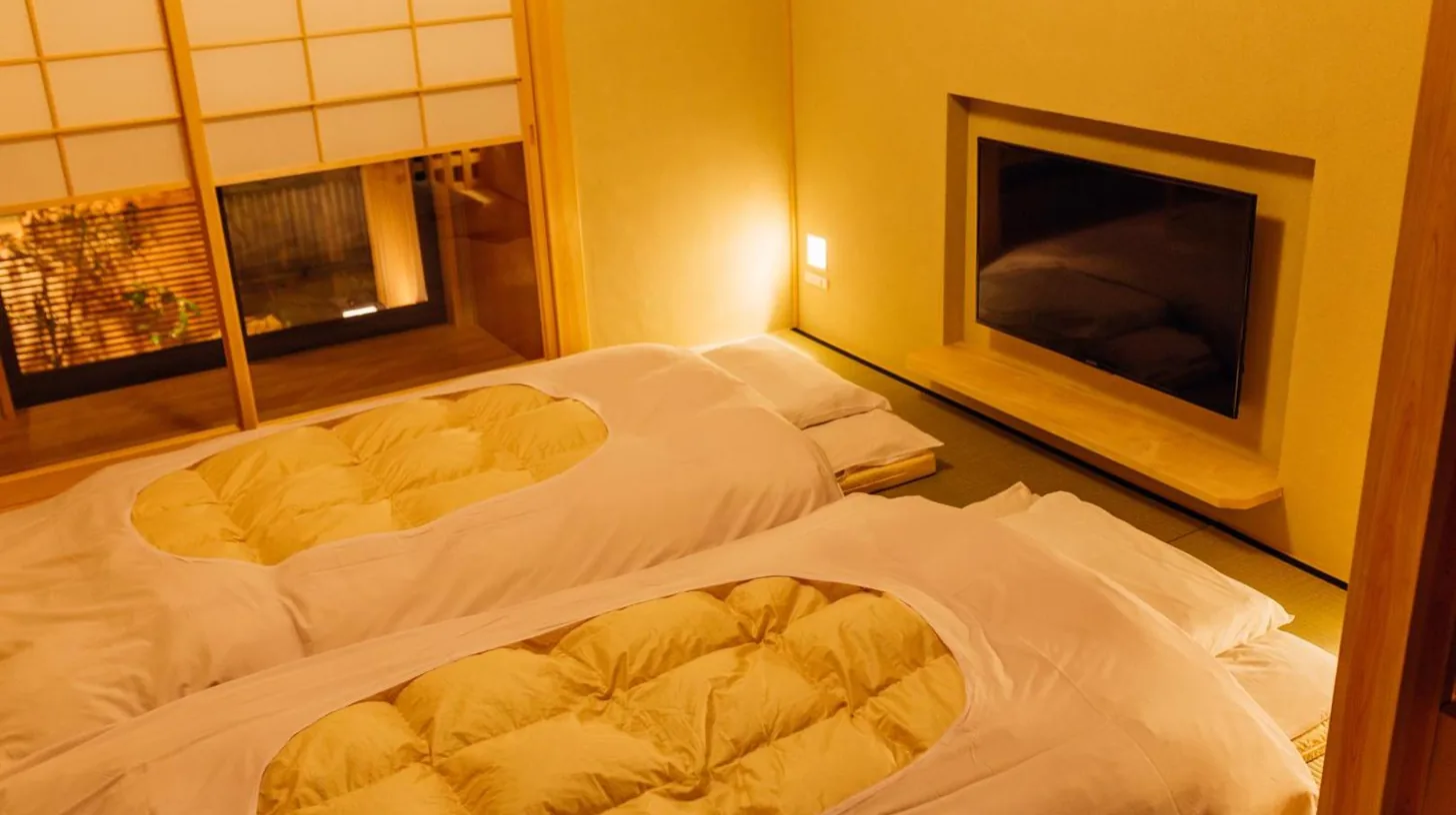 two beds in a room with a fireplace at Kyomachiya Suite Rikyu in Kyoto