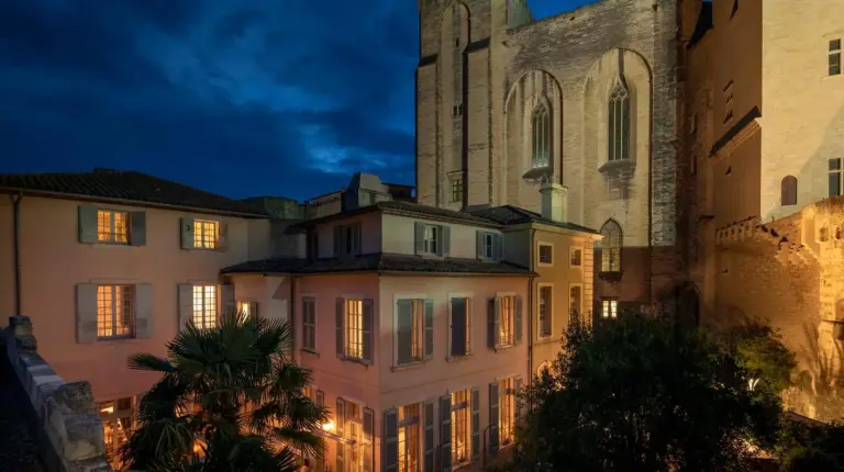 un grand bÃ¢timent avec une Ã©glise en arriÃ¨reâplan Ã  La Mirande Ã  Avignon