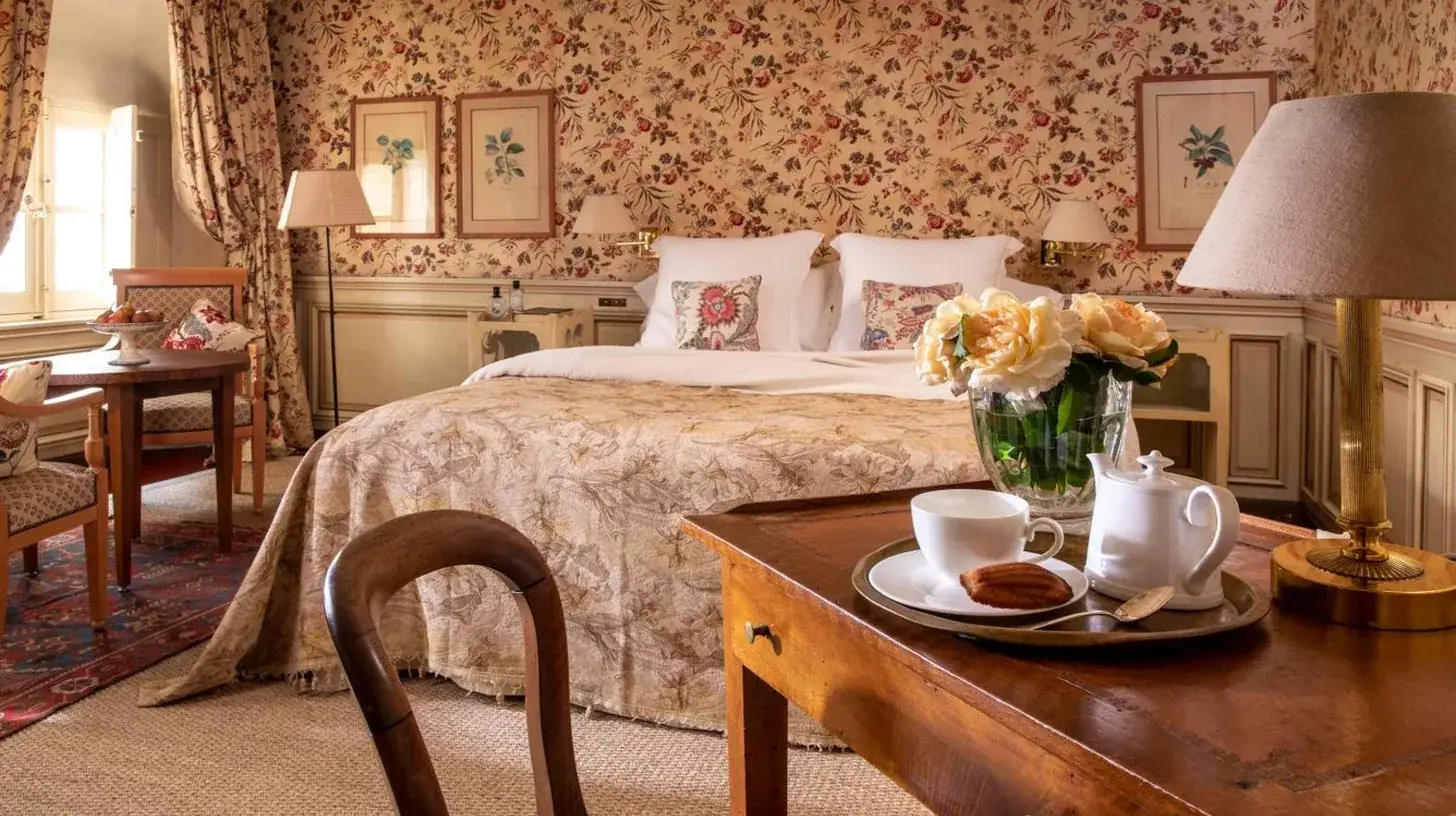 una habitaciÃ³n con una cama y una mesa de madera con un sidx sidx en La Mirande en AviÃ±Ã³n