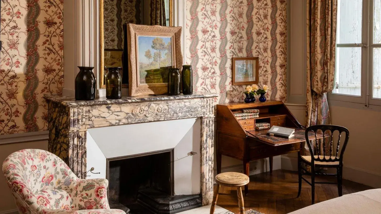 una sala de estar con chimenea, silla y mesa en La Mirande en AviÃ±Ã³n
