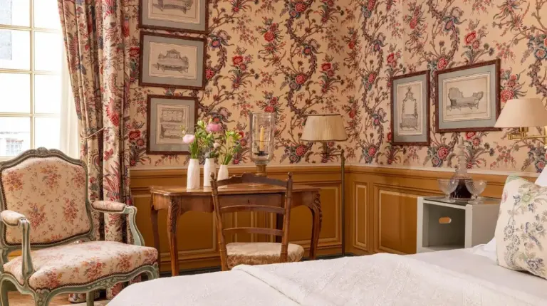una habitaciÃ³n con una cama, una mesa y una silla en La Mirande en AviÃ±Ã³n