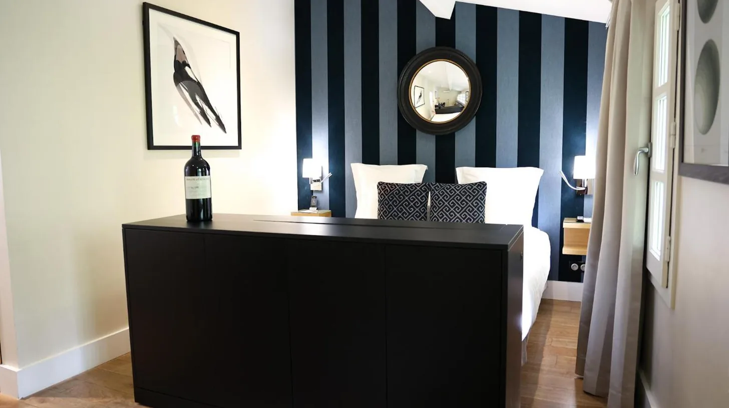 a bottle of wine on a dresser in a bedroom at Le Boutique Hotel & Spa in Bordeaux