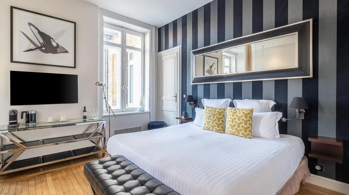 a bedroom with a bed and a desk and a television at Le Boutique Hotel & Spa in Bordeaux