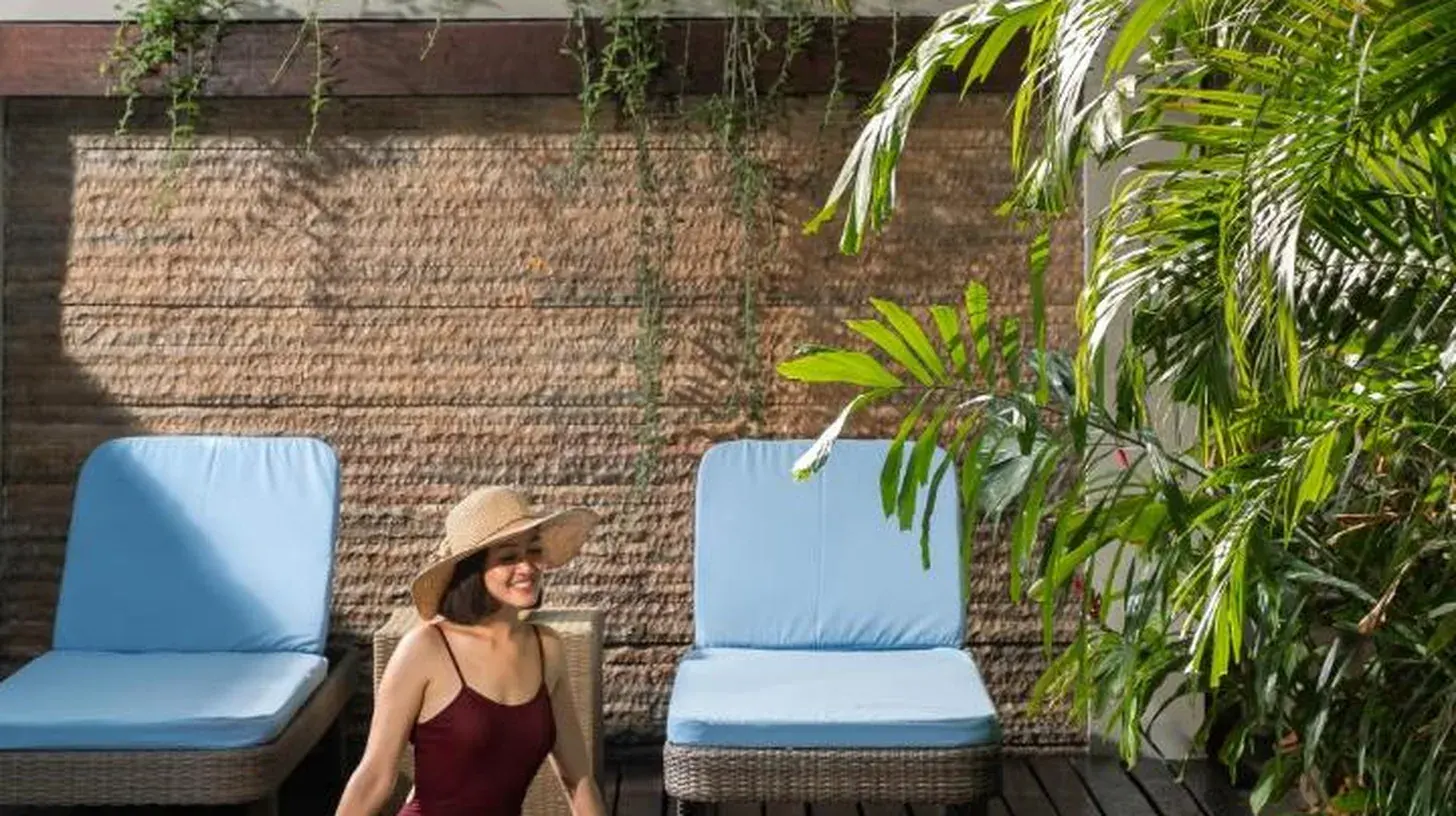 a woman sitting in the water next to a pool at Le Jardin Villas Seminyak in Seminyak