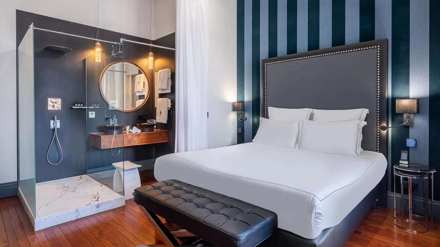 a bedroom with a large bed and a mirror at Le Palais Gallien Hôtel & Spa in Bordeaux