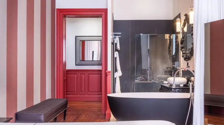 a bathroom with a bath tub and a red doorway at Le Palais Gallien Hôtel & Spa in Bordeaux