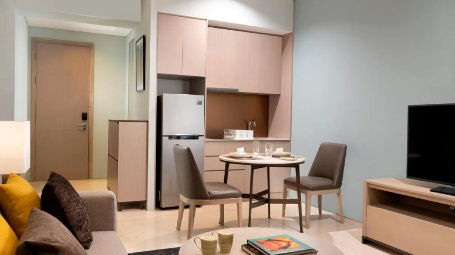 a living room with a couch and a table and a kitchen at Mangkuluhur Residences by Lorin in Jakarta