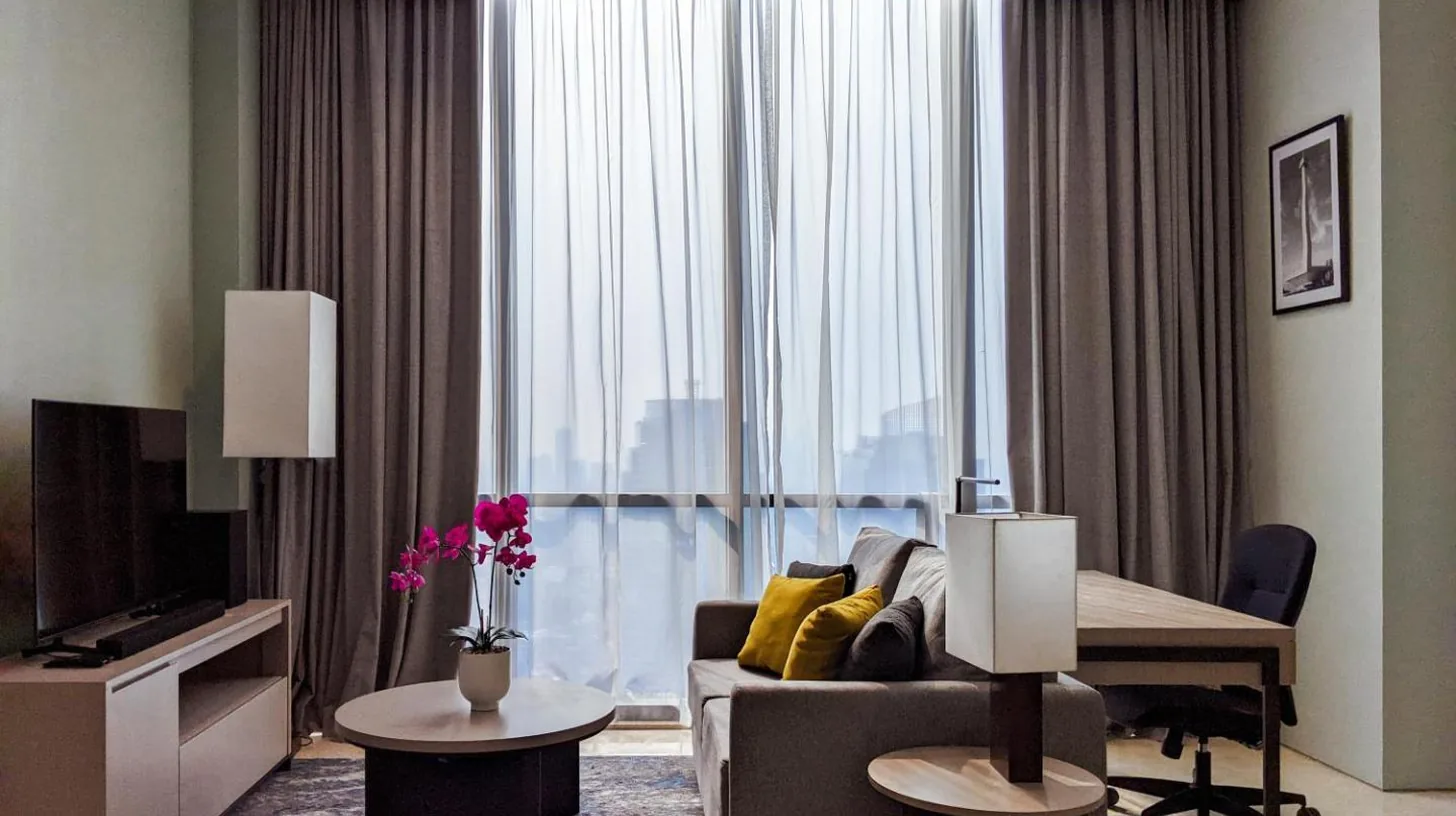 a living room with a couch and a table and a window at Mangkuluhur Residences by Lorin in Jakarta