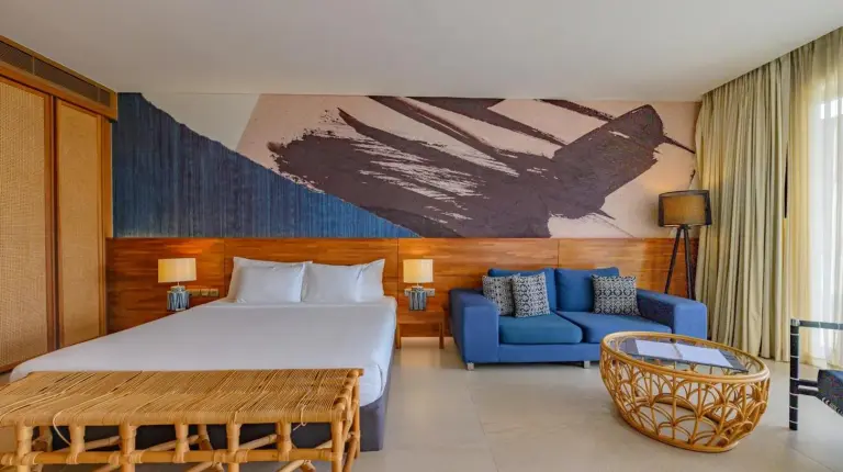 une chambre d'hôtel avec lit et canapé bleu au Mantra Samui Resort - Adults Only à Mae Nam
