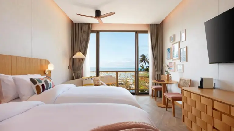 a hotel room with two beds and a large window at Marasca Samui - Small Luxury Hotels of the World in Chaweng