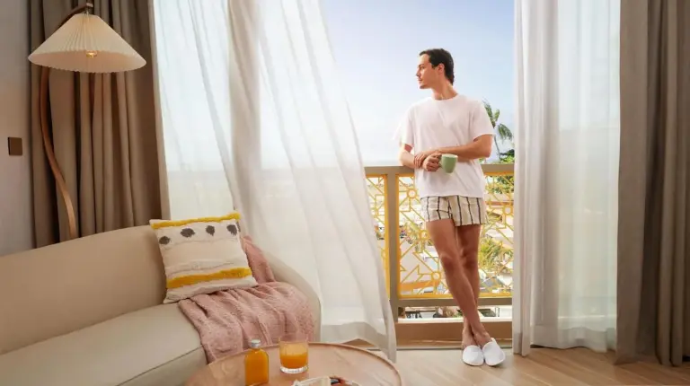 a man standing in a living room looking out the window at Marasca Samui - Small Luxury Hotels of the World in Chaweng