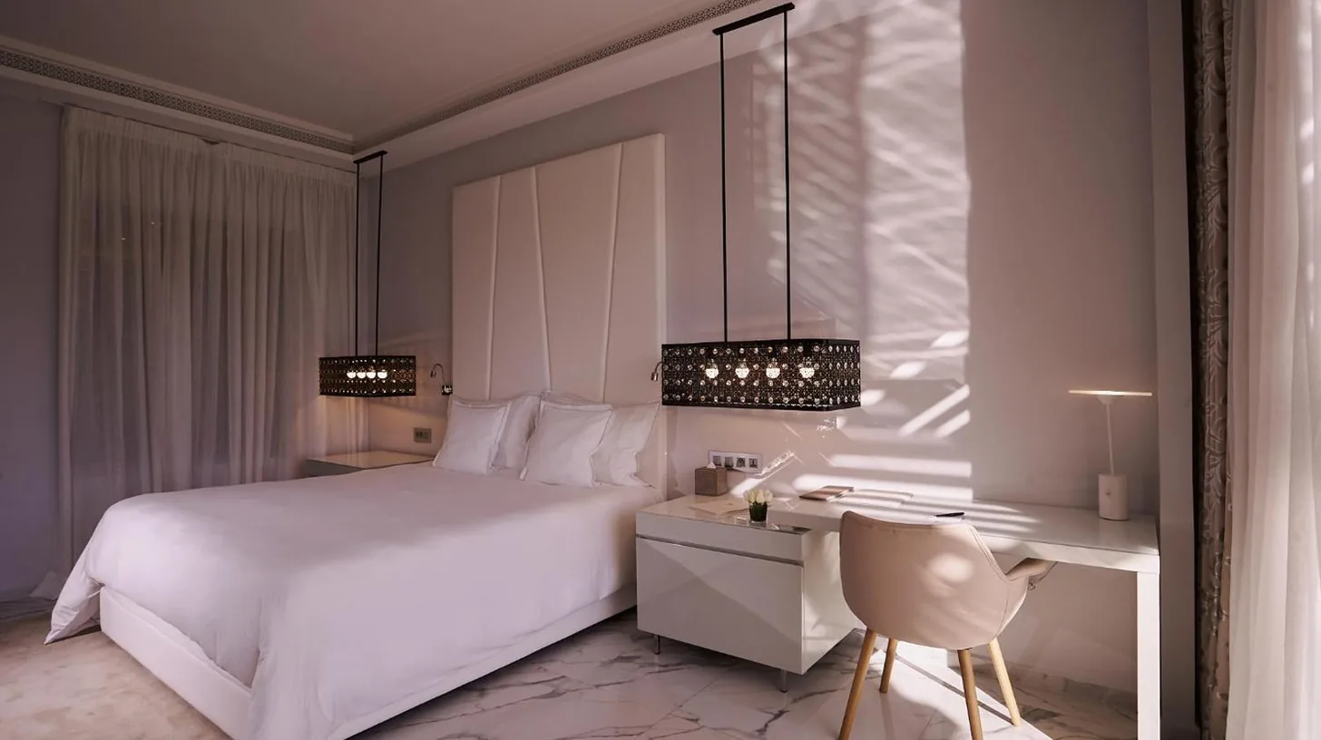 a bedroom with a white bed and a desk and a chair at Marchica Lagoon Resort in Nador