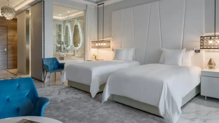 a hotel room with two beds and a blue chair at Marchica Lagoon Resort in Nador