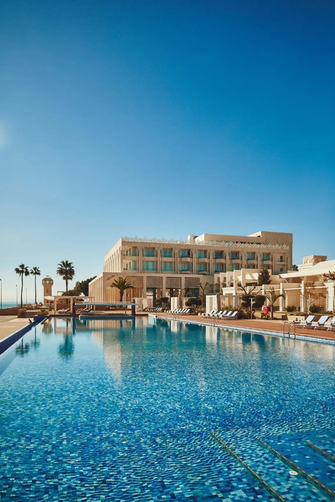 Marchica Lagoon Resort pool area featuring blue waters and palm trees