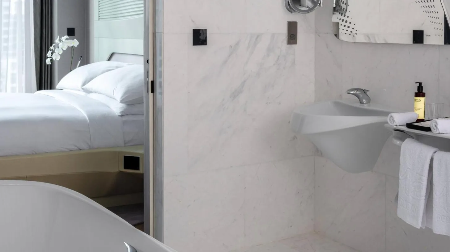 un baño con una ducha, un lavabo y una cama en ME by Meliá Dubai Residences en Dubái