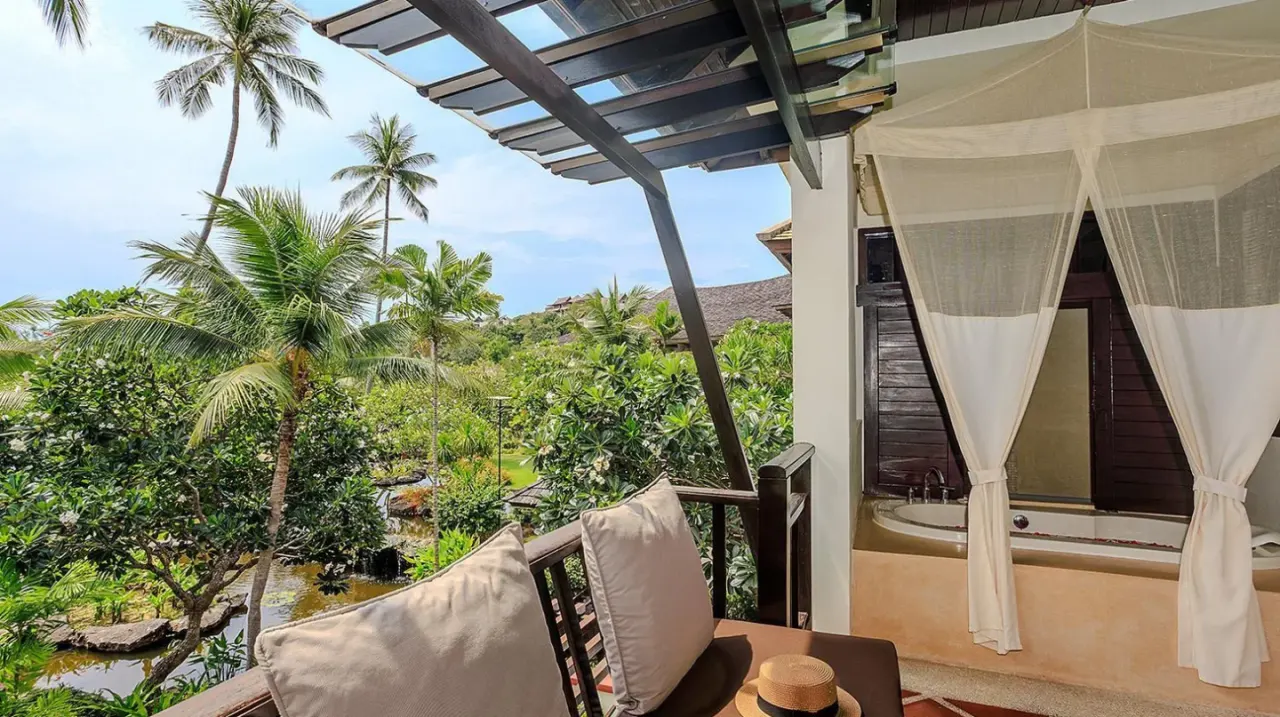 Balkon mit Tisch, Stühlen und Palmen im Melati Beach Resort & Spa am Choeng Mon Beach