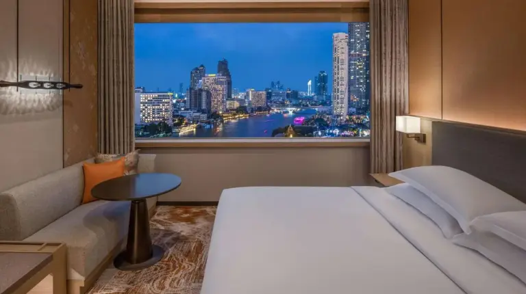 a hotel room with a bed and a large window at Millennium Hilton Bangkok in Bangkok