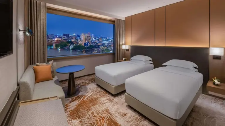 a living room and dining room with a view of the city at Millennium Hilton Bangkok in Bangkok