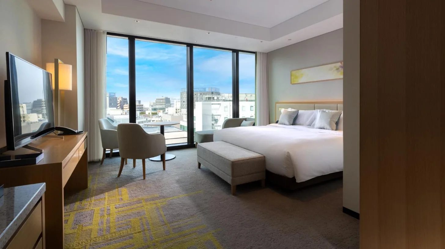 a hotel room with a bed and a large window at Miyako Hotel Hakata in Fukuoka