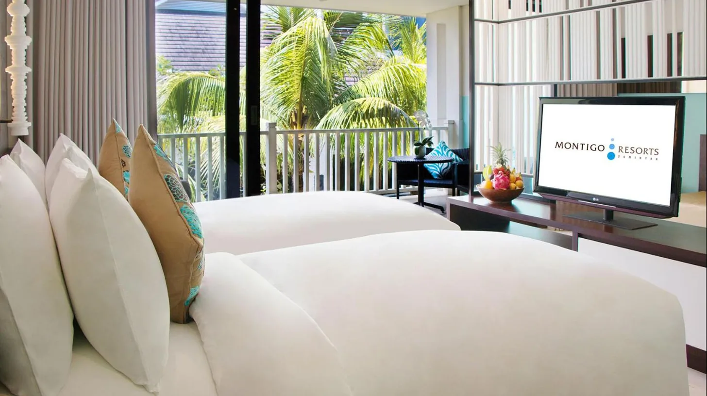a bedroom with two beds and a flat screen tv at Montigo Resorts Seminyak in Seminyak