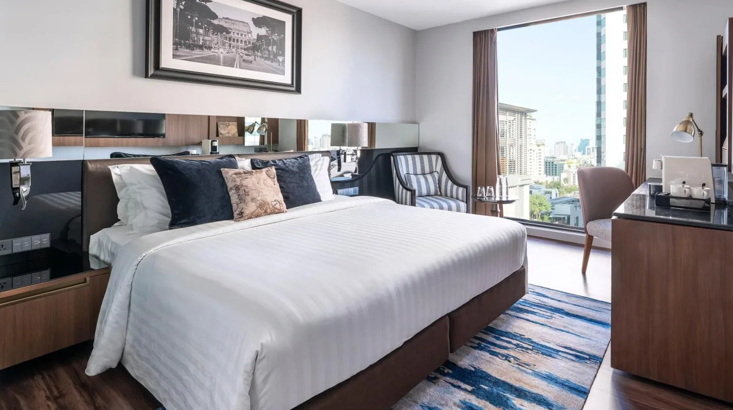 a bedroom with a large bed and a large window at Montraj Continent Sukhumvit Bangkok in Bangkok