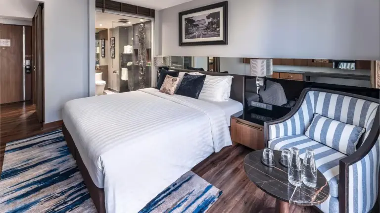 a hotel room with a bed and a chair at Montraj Continent Sukhumvit Bangkok in Bangkok