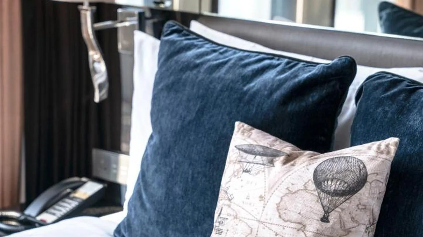 a bed with blue pillows and a pillow on it at Montraj Continent Sukhumvit Bangkok in Bangkok
