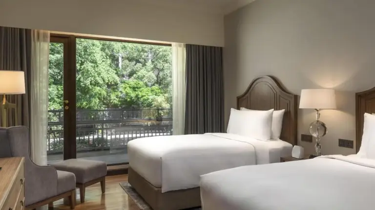 a hotel room with two beds and a window at Mövenpick BDMS Wellness Resort Bangkok in Bangkok