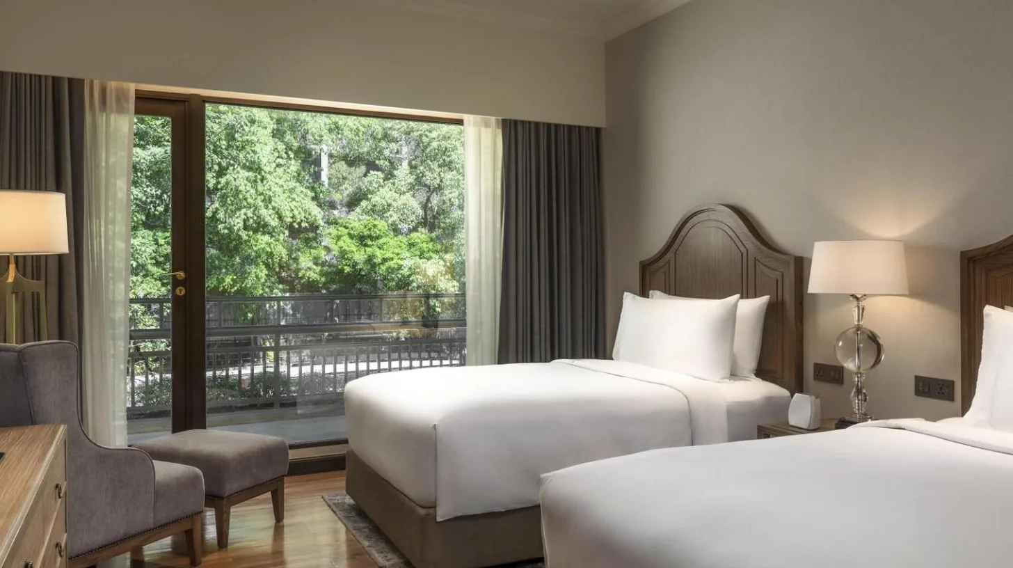 a hotel room with two beds and a window at Mövenpick BDMS Wellness Resort Bangkok in Bangkok