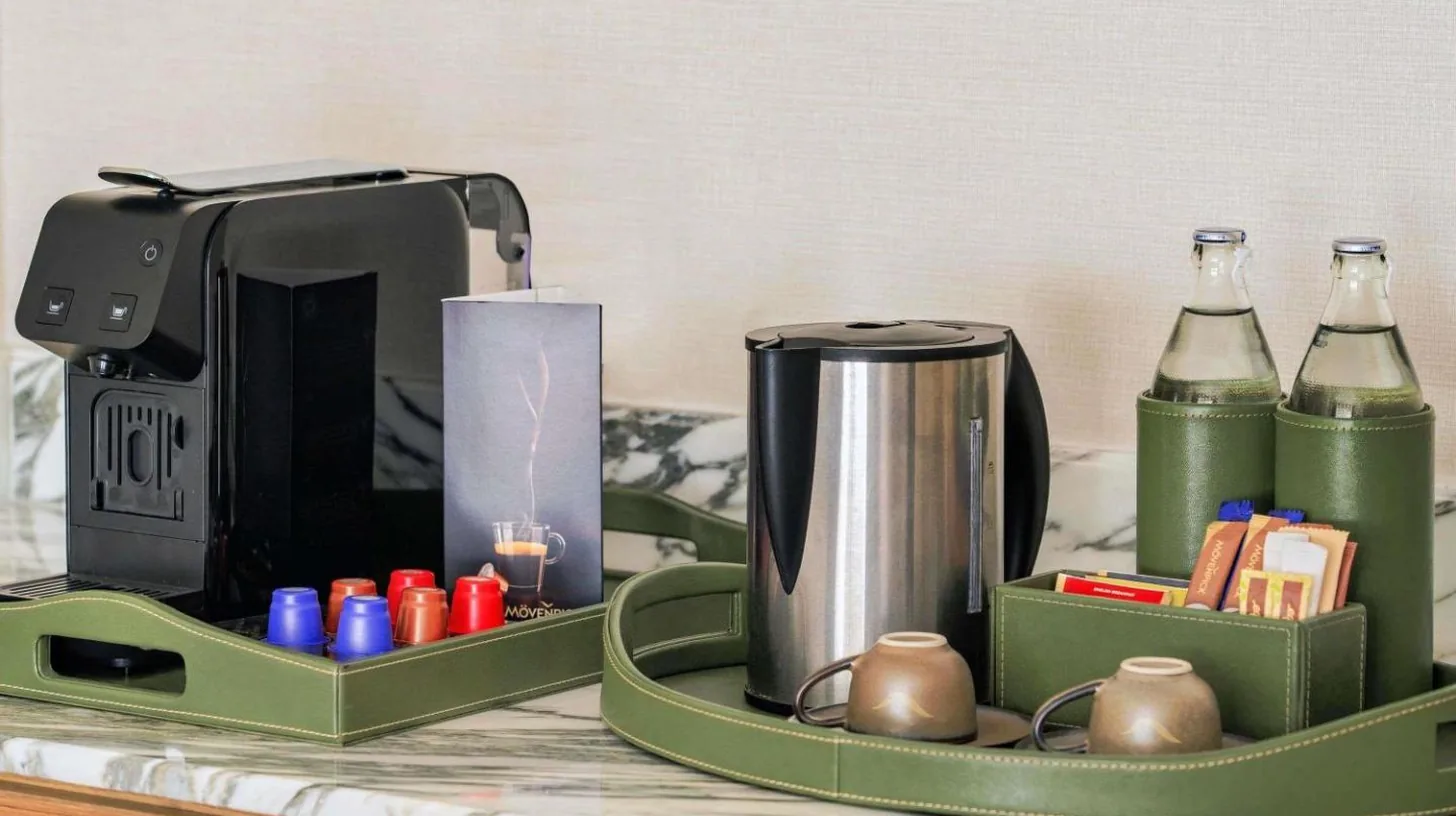 a green tray with a coffee maker and bottles on a counter at Mövenpick BDMS Wellness Resort Bangkok in Bangkok