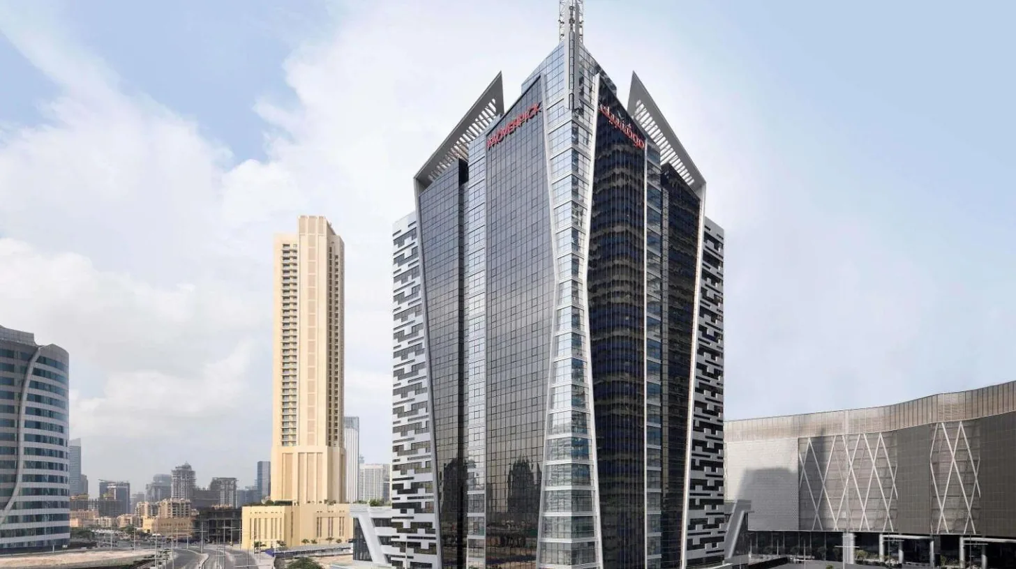 a tall building with a cross on top of it at Mövenpick Hotel Apartments Downtown Dubai in Dubai