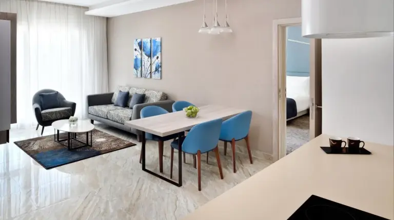 a living room with a table and blue chairs at Mövenpick Hotel Apartments Downtown Dubai in Dubai