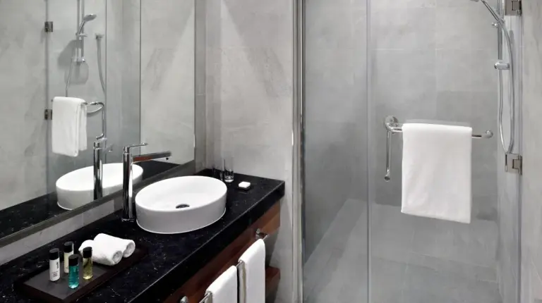 a bathroom with a sink and a glass shower at Mövenpick Hotel Apartments Downtown Dubai in Dubai