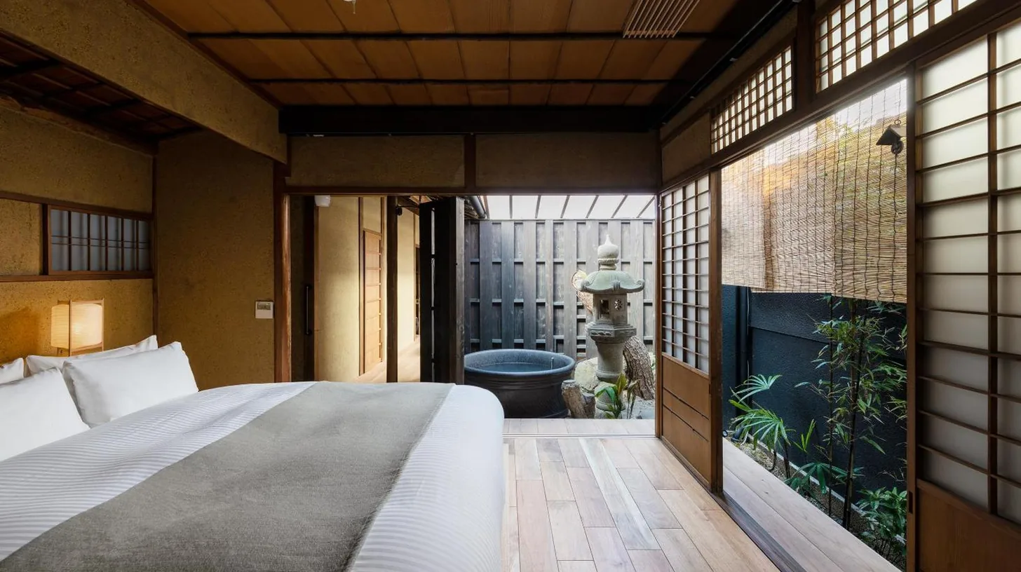 a bedroom with a bed in a room with a garden at Nazuna Kyoto Gosho in Kyoto