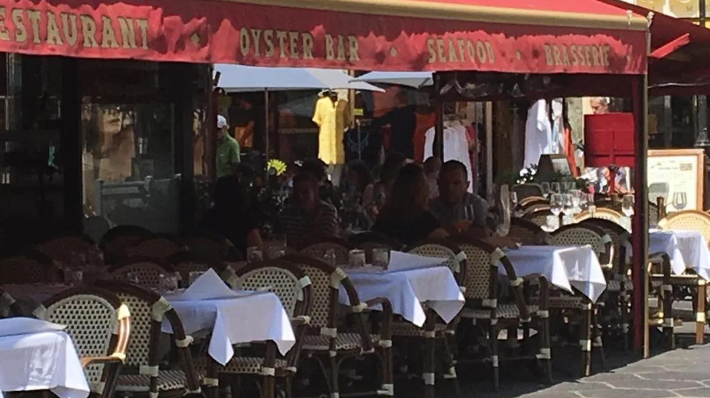 an outdoor restaurant with tables with white umbrellas at New central nice sea down town in Nice