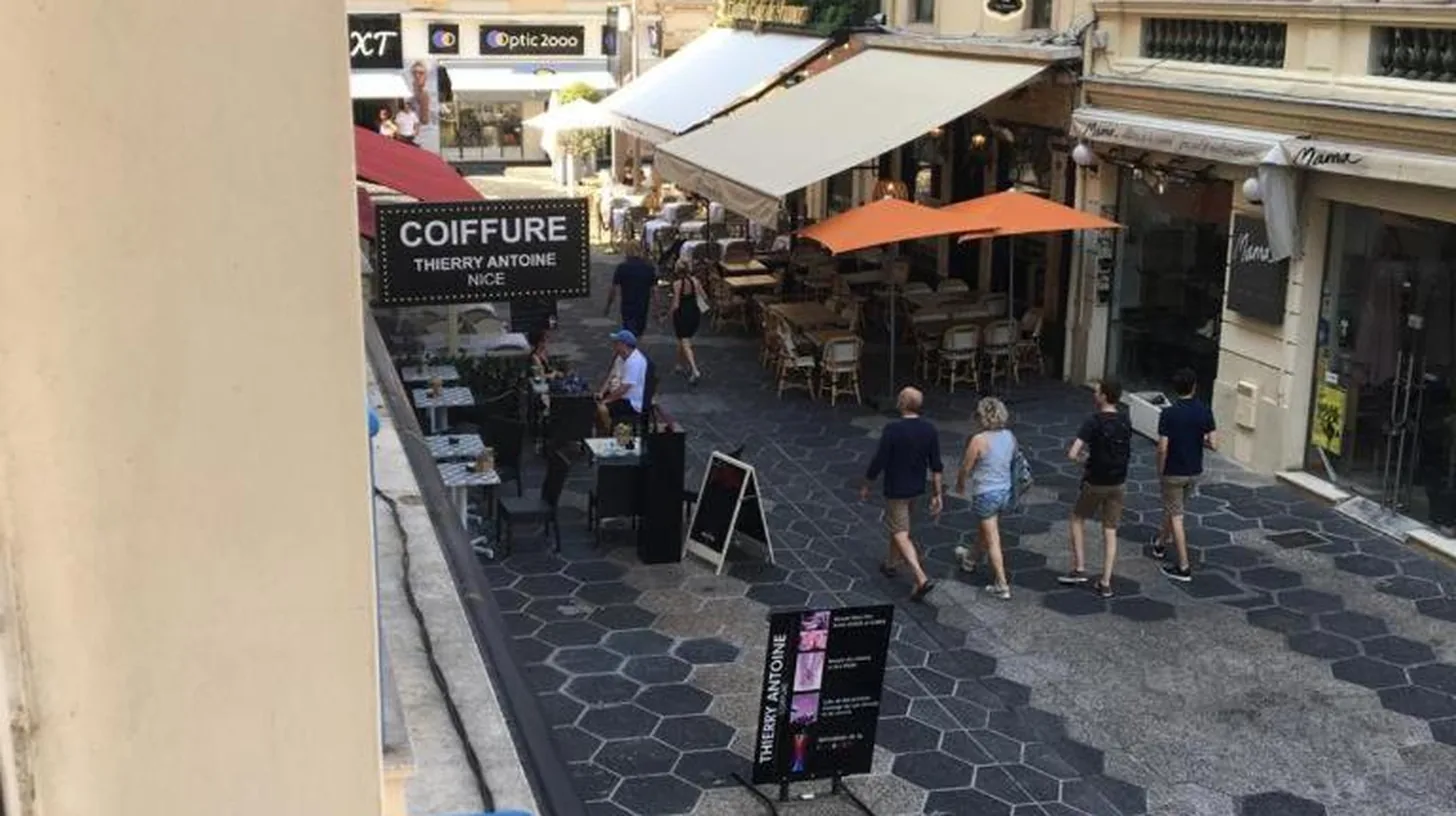 a group of people walking down a street with buildings at New central nice sea down town in Nice