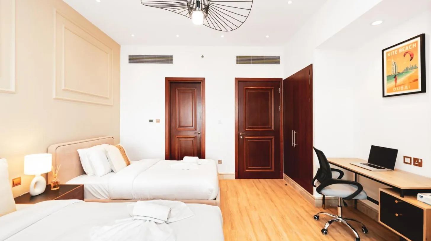 a bedroom with two beds and a desk with a computer at New Fairmont Residence with private beach on Palm Jumeirah in Dubai